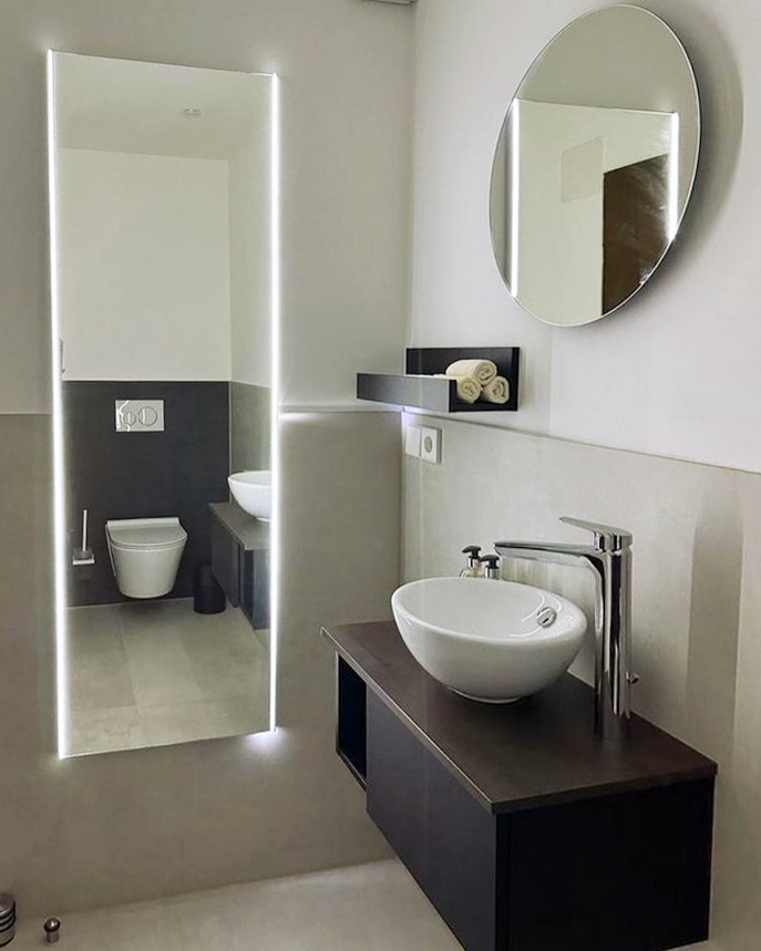 Modernes Badezimmer mit hellgrauen Fliesen, hängendem Waschtisch und Spiegeln